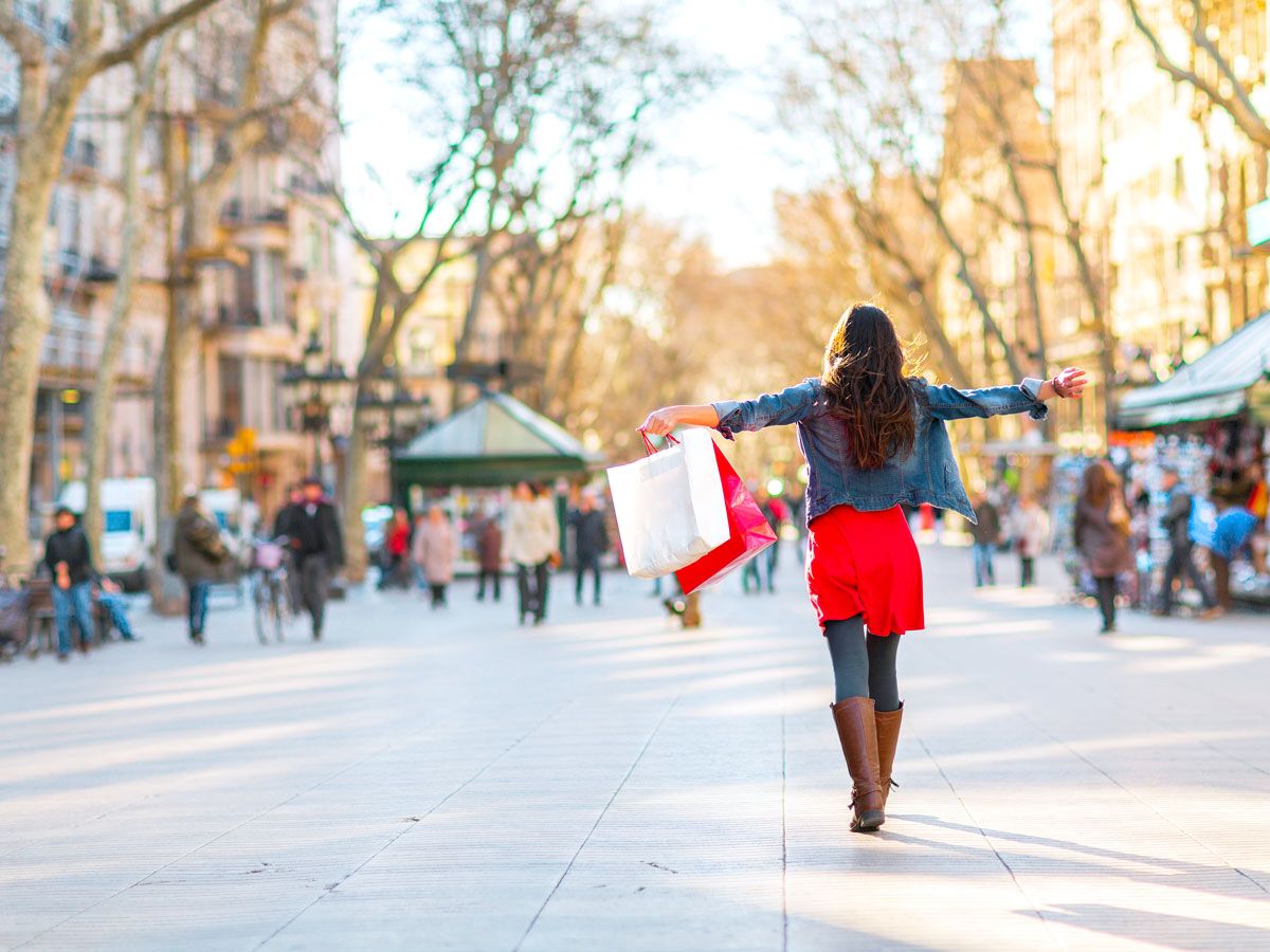 Person holding shopping bags with arms outstretched on Barcelona street