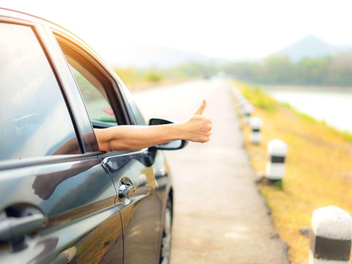 Person giving thumbs up out of car window