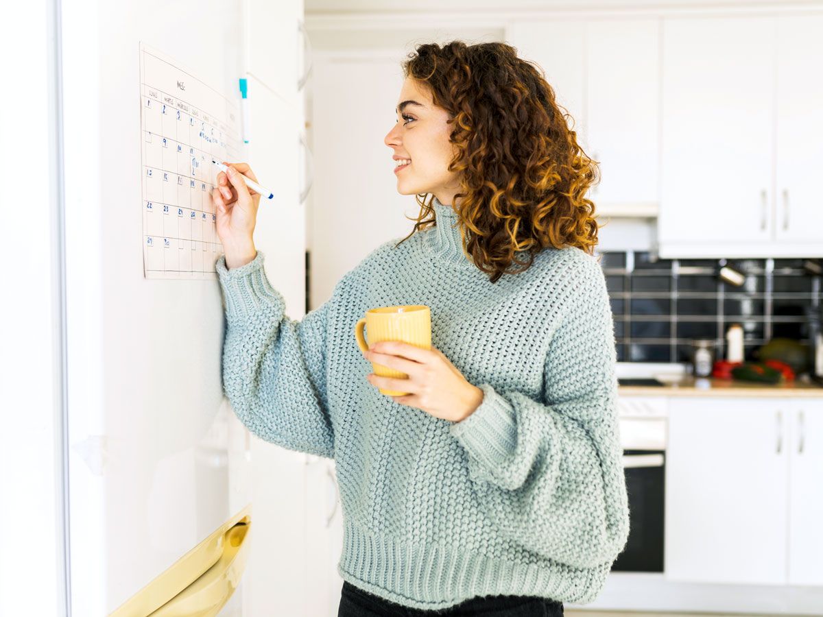 Person marking calendar in kitchen