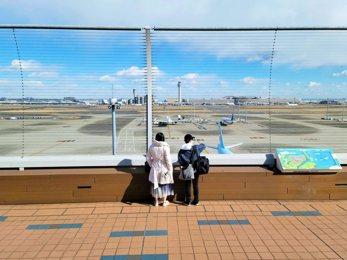 Two people observing planes from observation deck at Tokyo Haneda Airport in Japan