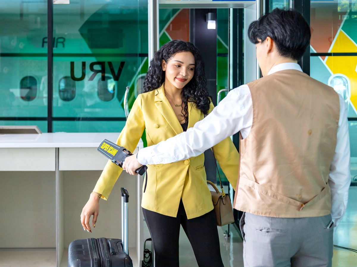 Security officer using wand to scan traveler