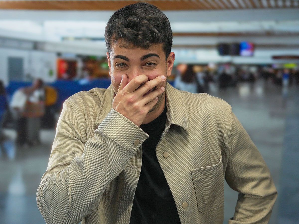 Man covering mouth with laughter in airport terminal