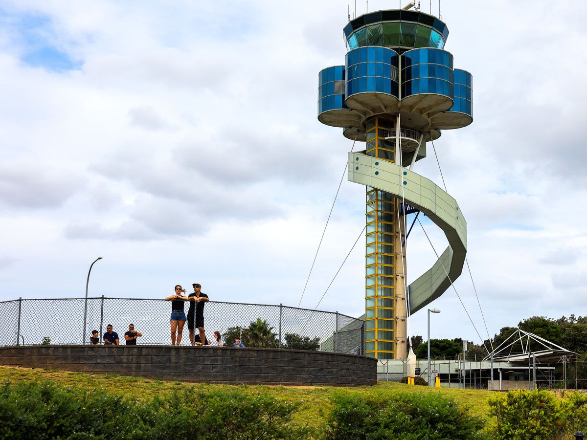 Enthusiasts wathcing planes under the control tower at Sydney Airport, Australia