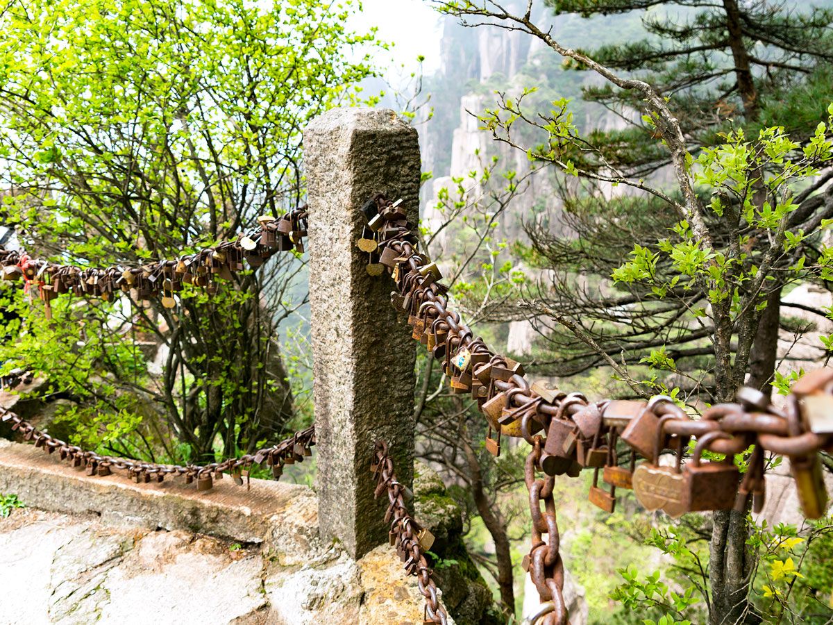Padlocks attached to railing overlooking Mount Huangshan in China