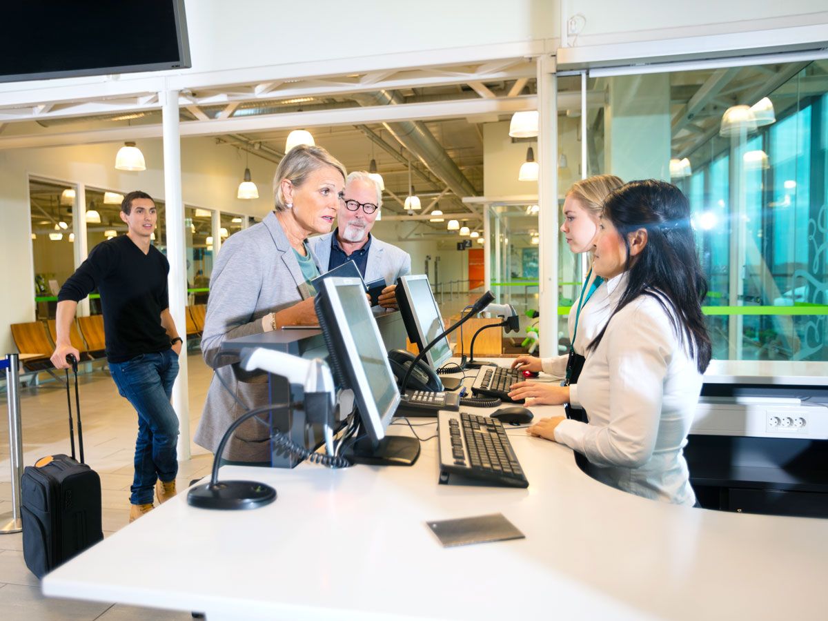 Passengers speaking with gate agents at airport counter