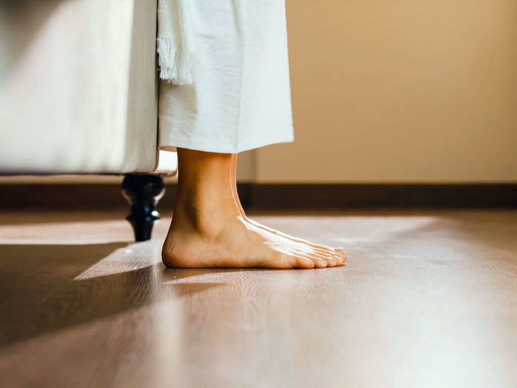 A person's bare feet on hardwood floors