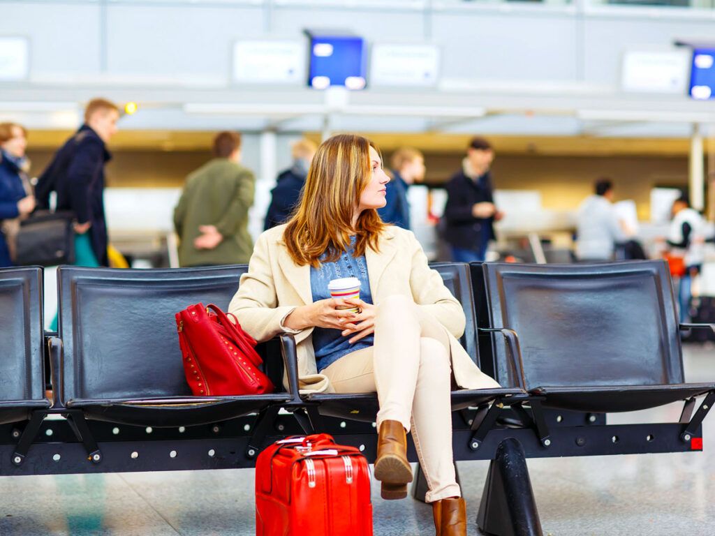 Passenger waiting at gate with cup of coffee