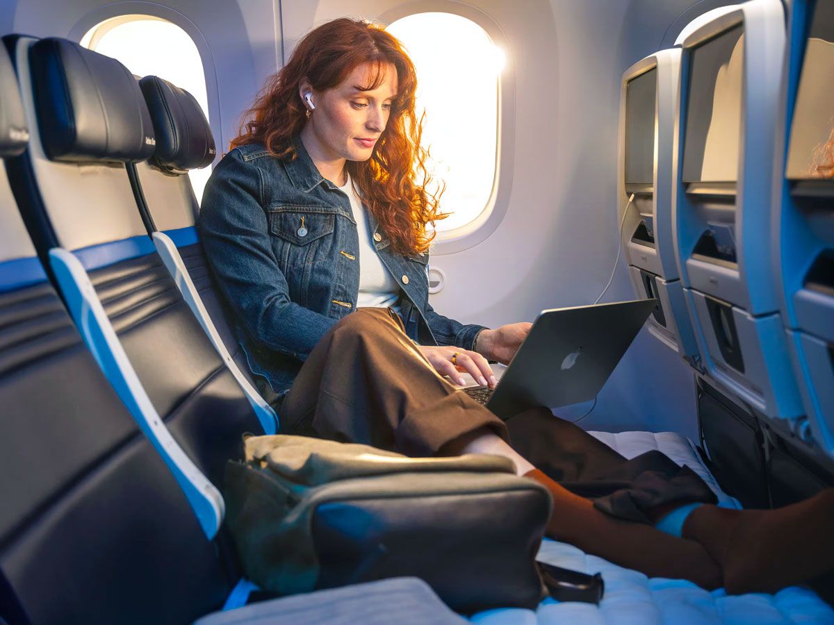Solo traveler working on laptop while resting legs in United Relax Row