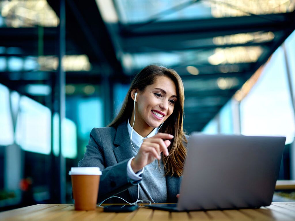 Airport lounge guest wearing headphones and working on laptop
