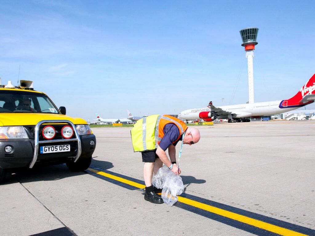 Inspector removing object on runway at airport