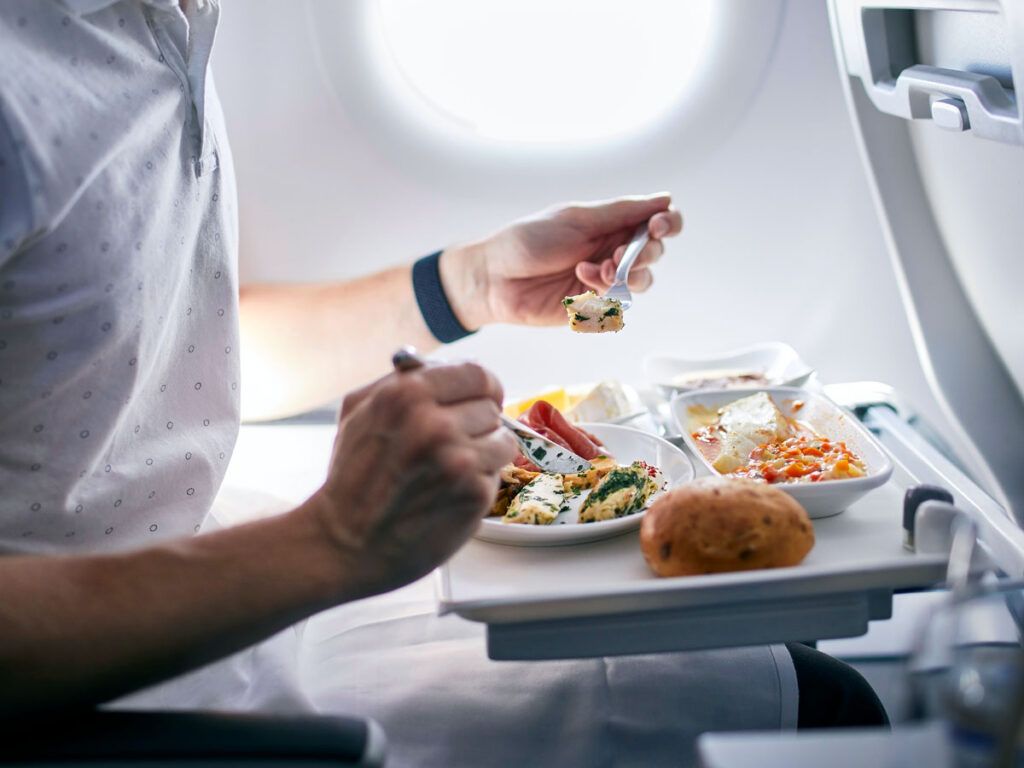 Passenger eating meal from seatback tray table