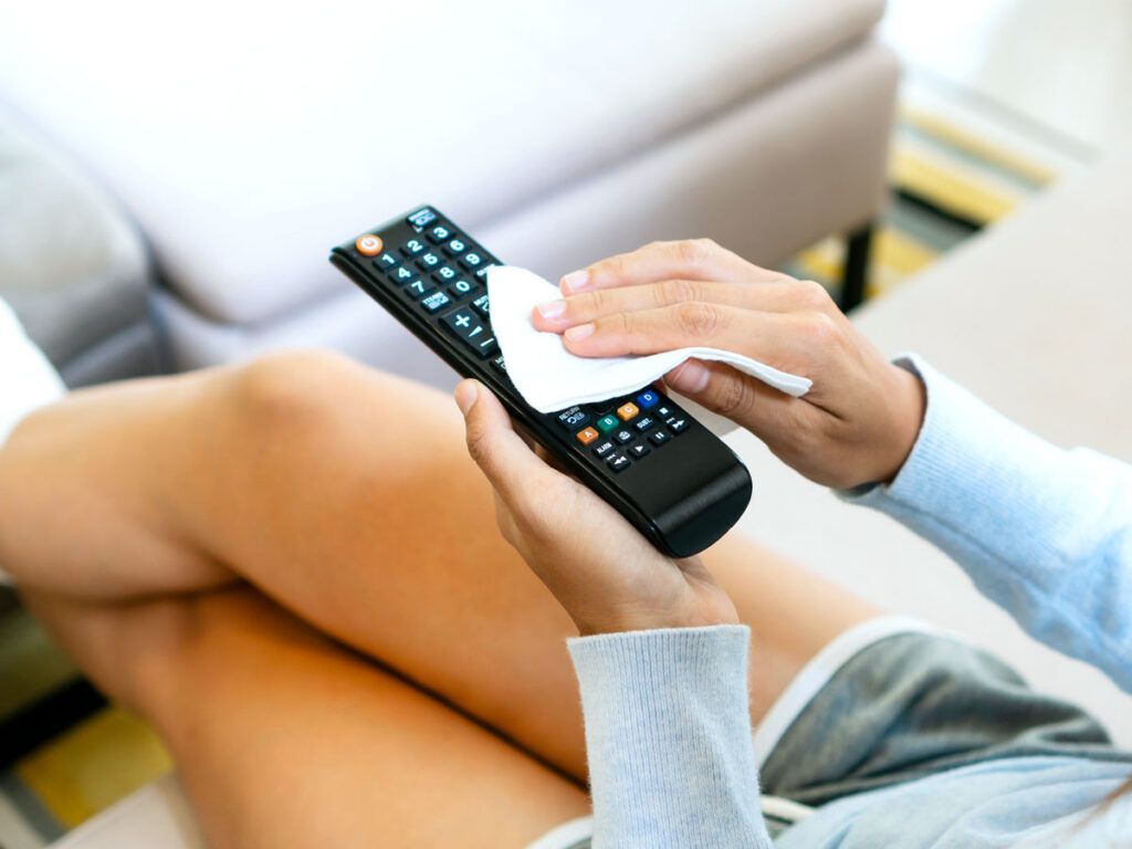 Person wiping TV remote
