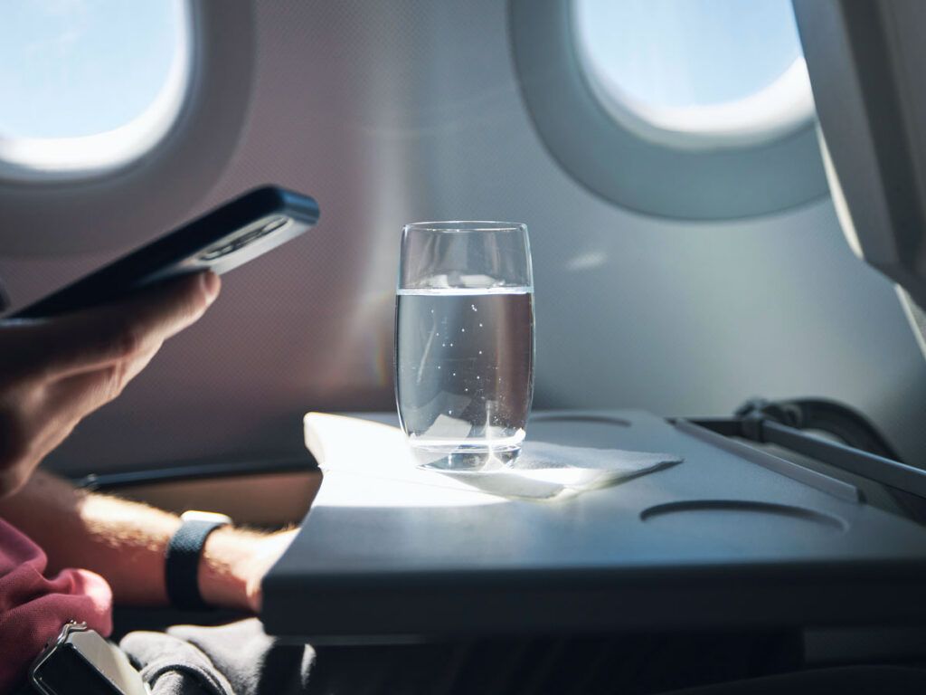 Passenger with glass of water on tray table