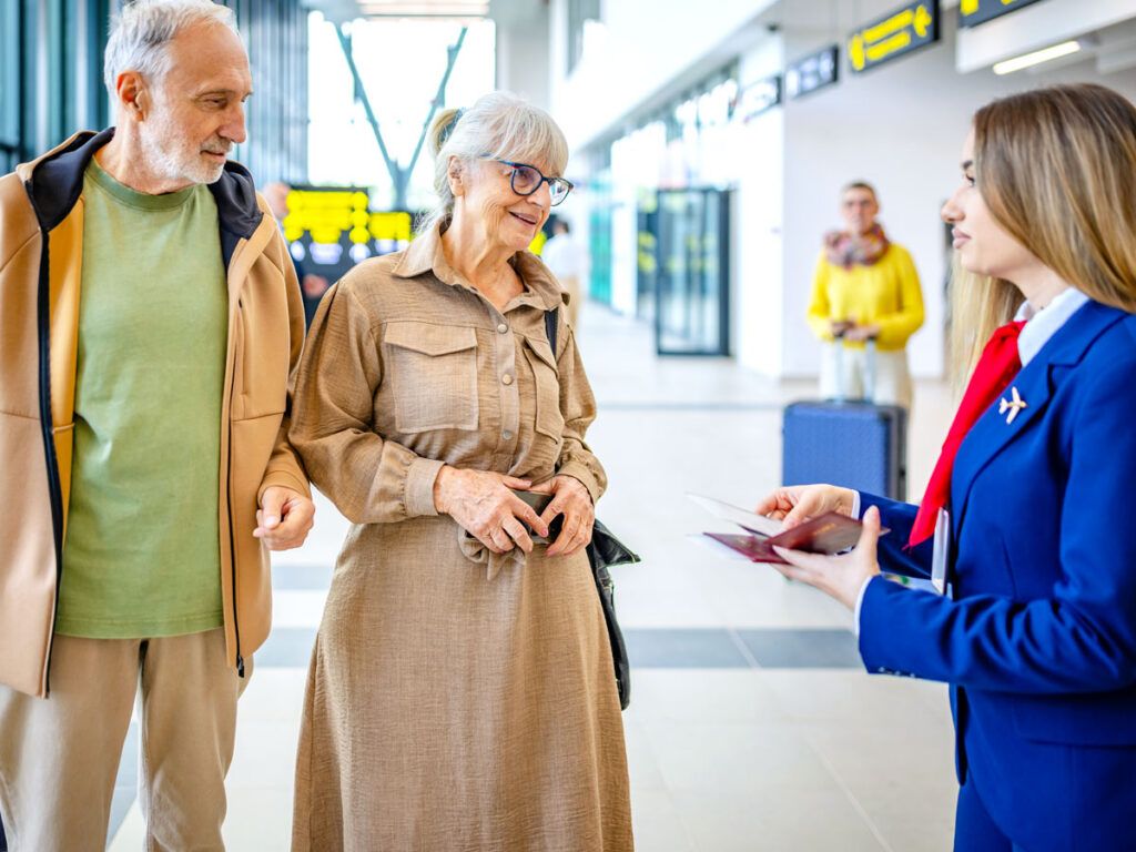 Travelers speaking with airport employee in terminal