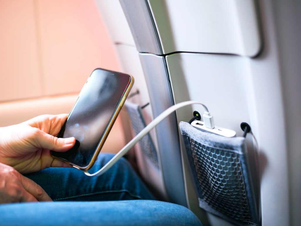 Traveler using portable charger in airplane seat