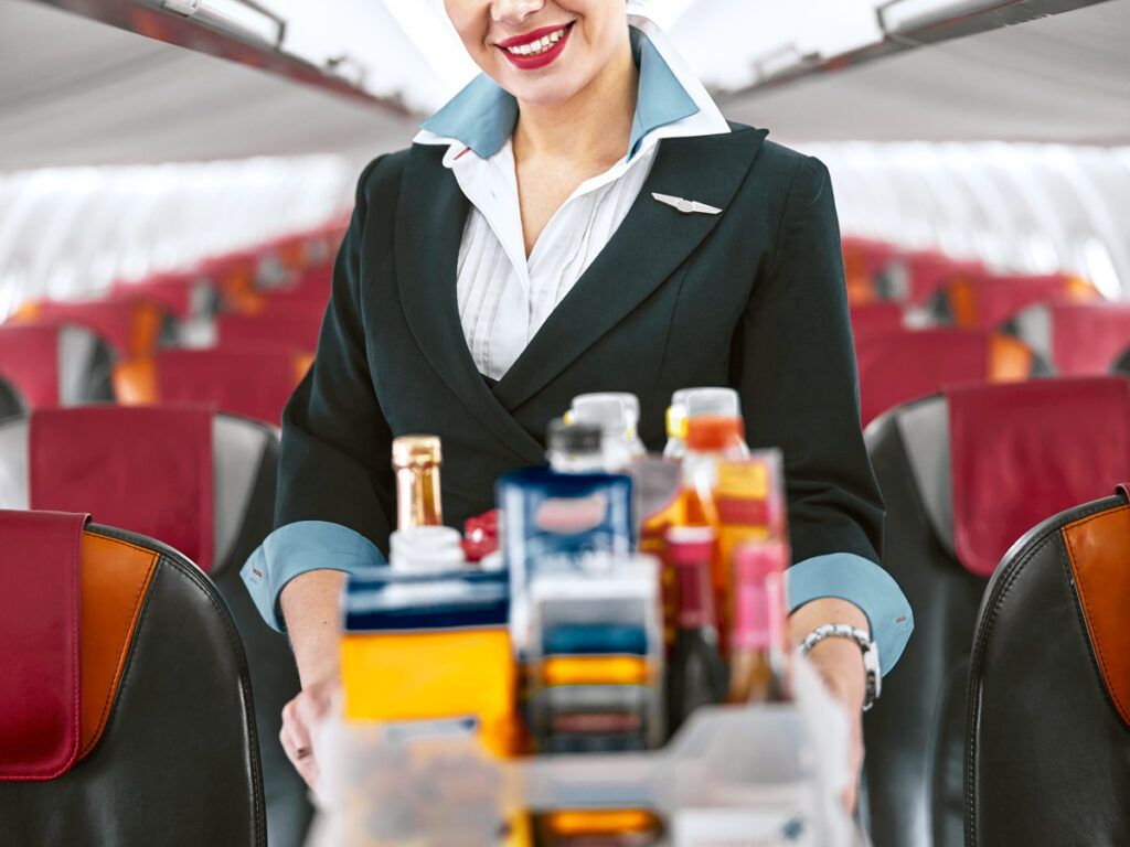 Flight attendant rolling beverage cart through aisle